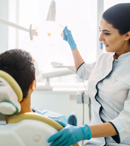 Boy in a dental cabinet, pediatric dentistry. The doctor examines the teeth of a small patient